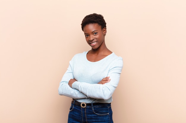 sorrindo para a câmera com os braços cruzados e uma expressão feliz, confiante e satisfeita, vista lateral