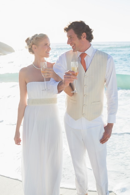 Foto sorrindo recém-casados ​​com champanhe ligando os braços