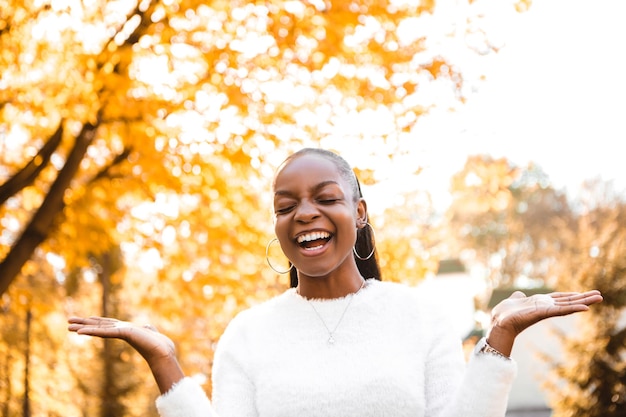 Sorrindo rindo mulher afro-americana em pé no parque da cidade, se divertindo com as mãos esticadas