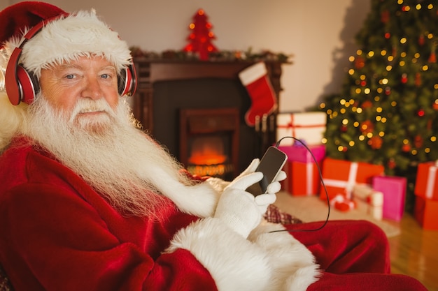 Sorrindo santa escutando música com seu smartphone