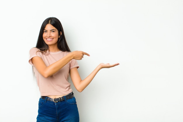 sorrindo, sentindo-se feliz, despreocupado e satisfeito, apontando para o conceito ou idéia no espaço da cópia ao lado