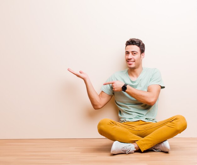 sorrindo, sentindo-se feliz, despreocupado e satisfeito, apontando para o conceito ou idéia no espaço da cópia ao lado