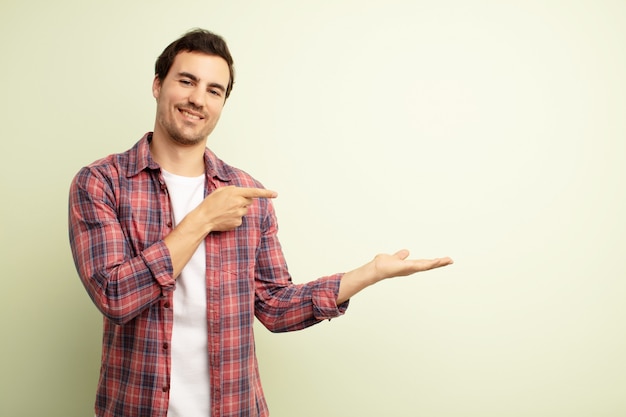 sorrindo, sentindo-se feliz, despreocupado e satisfeito, apontando para um conceito ou ideia no espaço da cópia ao lado