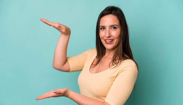 Sorrindo, sentindo-se feliz, positivo e satisfeito, segurando ou mostrando objeto ou conceito no espaço da cópia