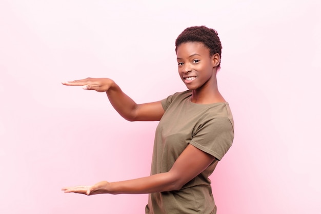 Sorrindo, sentindo-se feliz, positivo e satisfeito, segurando ou mostrando objeto ou conceito no espaço da cópia