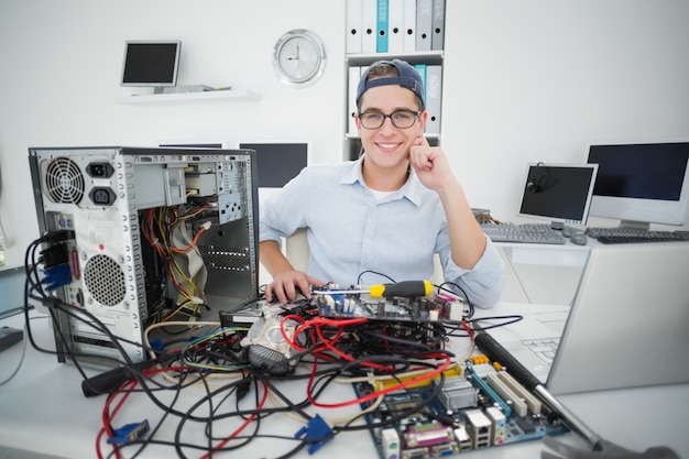 Sorrindo técnico trabalhando no computador quebrado em seu escritório