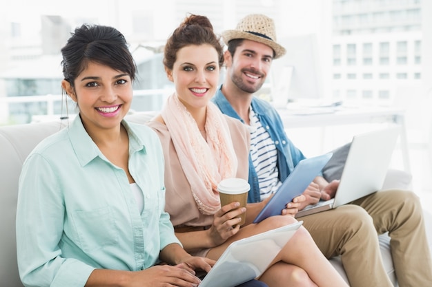 Sorrindo trabalho em equipe sentado no sofá olhando câmera