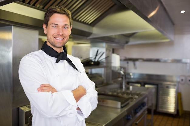 Sorrir cozinheiro masculino com os braços cruzados na cozinha