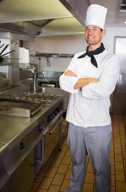 Sorrir cozinheiro masculino com os braços cruzados na cozinha