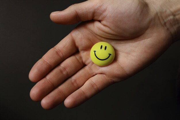 Sorriso amarelo na palma aberta Rosto sorridente redondo na mão Conceito de amizade Humor amigável