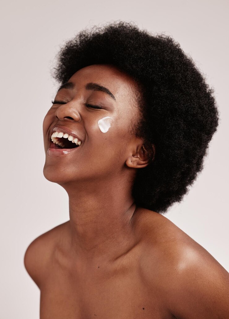 Foto sorriso de beleza e mulher negra com creme no rosto afro e publicidade animada para promoção de produtos de pele de luxo cosméticos dermatológicos e salão facial para modelo feliz isolado no fundo do estúdio