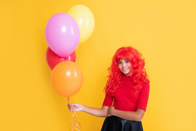 Sorriso de criança com balão de festa em fundo amarelo