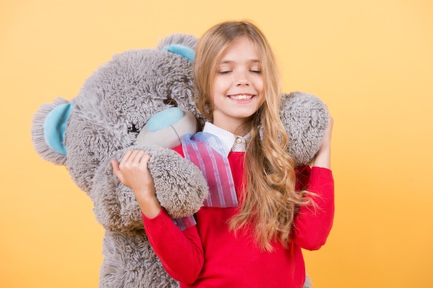 Sorriso de criança com brinquedo macio cinza