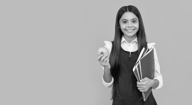 Sorriso de criança de escola feliz segurando maçã e livros laranja cópia de fundo espaço escolar
