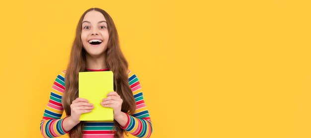 Sorriso de criança de menina feliz segurando livro escolar fundo amarelo escolar Banner de estudante estudante Retrato de aluno de escola com espaço de cópia