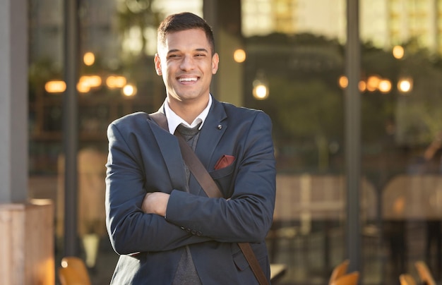 Sorriso de empresário e retrato na cidade urbana em pé de braços cruzados para sucesso mentalidade positiva e felicidade ao ar livre Homem corporativo rosto feliz e confiante para realização de negócios na paisagem urbana