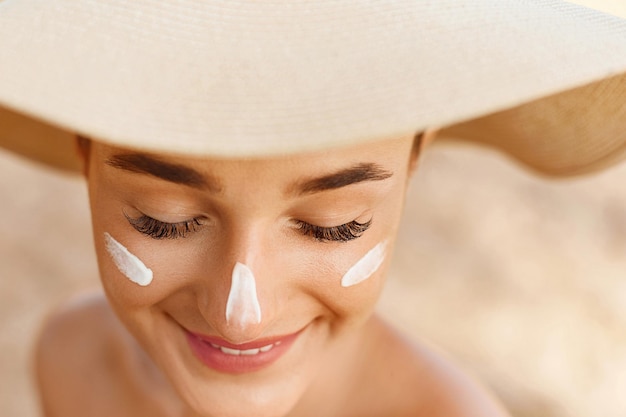 Sorriso de mulher aplicando protetor solar no rosto Cuidados com a pele Corpo Proteção solar Protetor solar