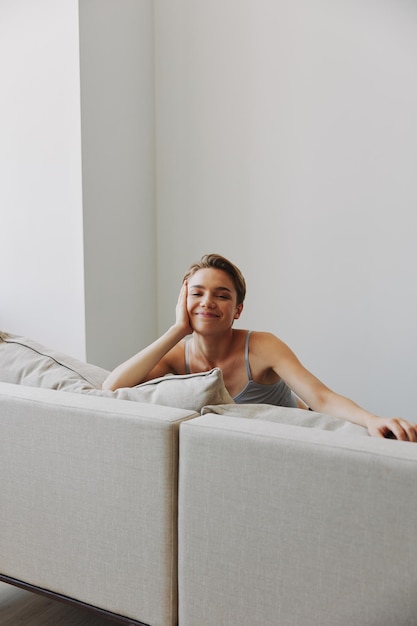 Sorriso de mulher feliz deitado em casa no sofá relaxando em um fim de semana em casa com um corte de cabelo curto sem filtros em um espaço de cópia gratuita de fundo branco