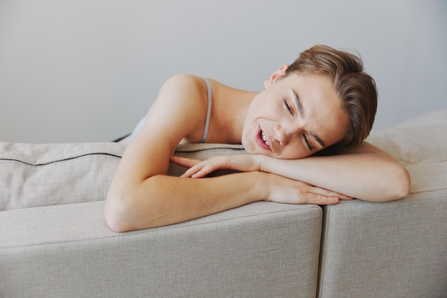 Sorriso de mulher feliz deitado em casa no sofá relaxando em um fim de semana em casa com um corte de cabelo curto sem filtros em um espaço de cópia gratuita de fundo branco