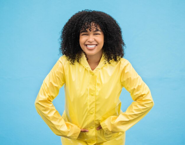 Sorriso de mulher negra e felicidade em retrato com moda de capa de chuva para o inverno e beleza isolada em fundo azul Feliz em estilo de estúdio e jaqueta com maquete feminina na moda e animada