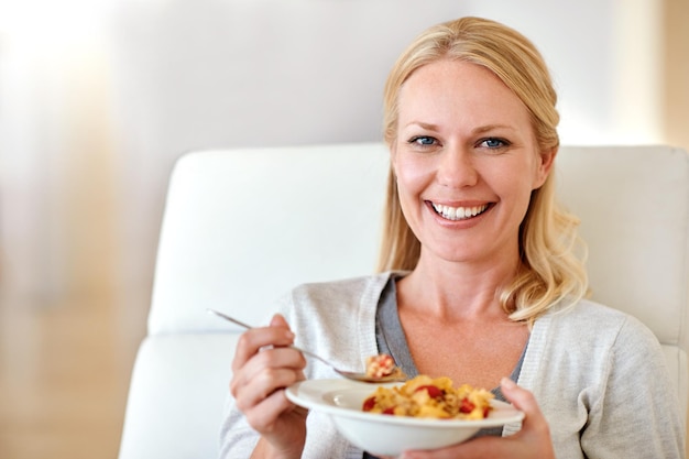 Sorriso de retrato de mulher feliz e cereais para café da manhã saudável ou dieta matinal na sala de estar em casa Pessoa do sexo feminino sorrindo com tigela de comida de trigo ou flocos de milho para nutrição de saúde ou fibra