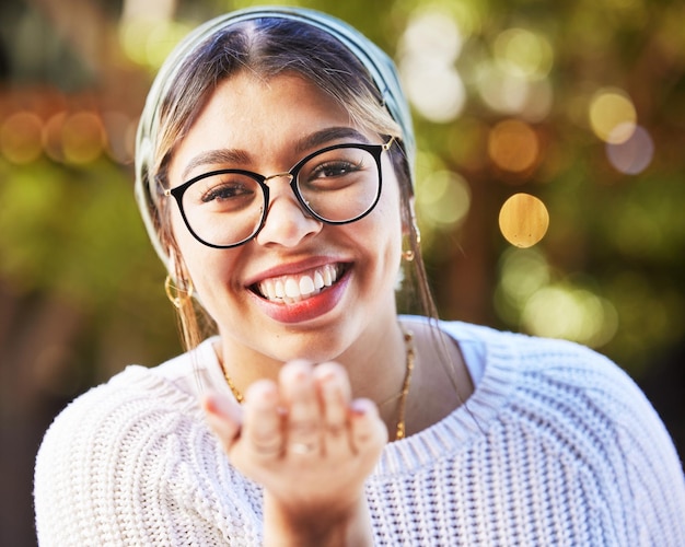 Foto sorriso de retrato e mandando um beijo com uma mulher em um fundo verde natural para amor ou romance óculos de rosto e flerte com uma jovem feliz em pé em um jardim no dia dos namorados