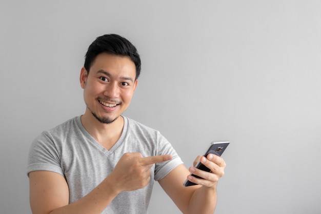 Sorriso e cara feliz do uso do homem e toque de seu smartphone.