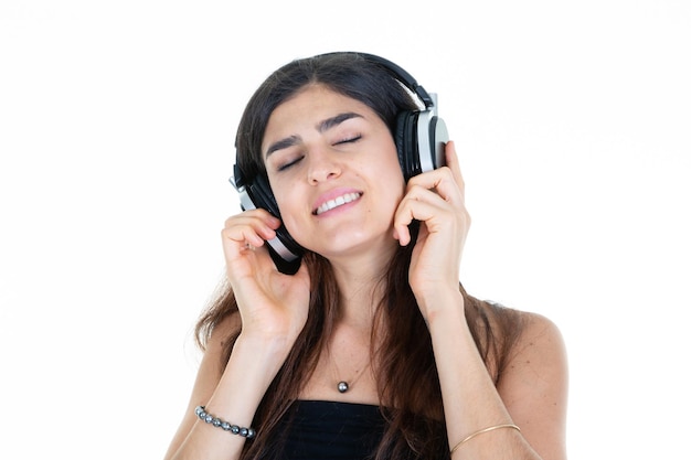 Sorriso feliz da jovem mulher com fones de ouvido na cabeça, olhos fechados, emocional positivo no fundo branco