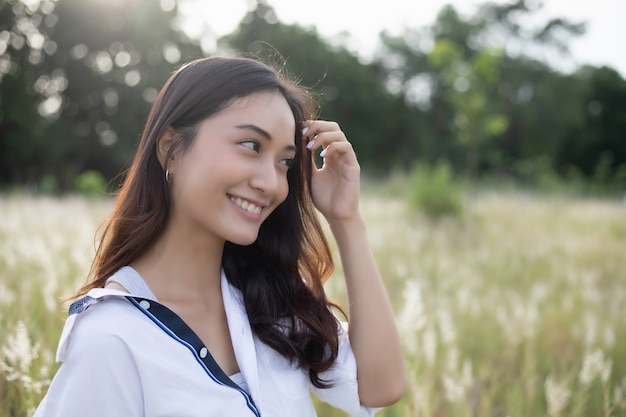 Sorriso feliz de mulheres asiáticas em relaxar o tempo no pasto e grama