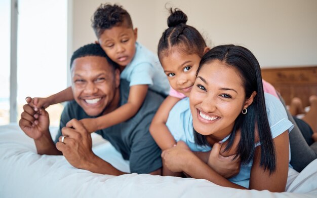 Sorriso feliz e retrato de uma família em um quarto para relaxar, brincar e se unir em sua casa Amor feliz e pais relaxando com seus filhos enquanto brincam em uma cama em sua casa