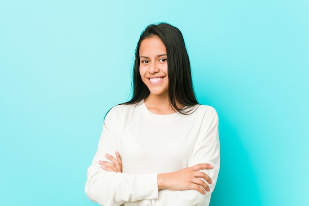 Sorriso latino-americano bonito novo da mulher seguro com braços cruzados.