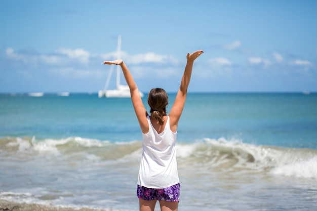 Sorriso Liberdade e felicidade mulher na praia. Ela está curtindo a natureza serena do oceano durante viagens de férias ao ar livre