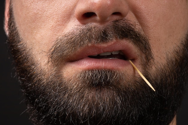 Sorriso mau closeup barbudo rosto de homem com palito nos dentes conceito de emoções malignas de bandido dan ...