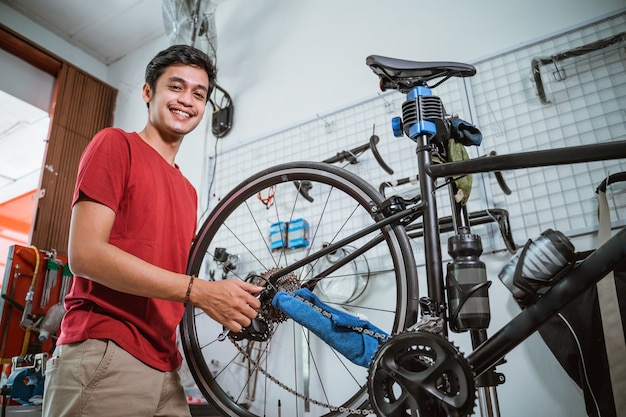 Foto sorriso mecânico enquanto trabalha aperta o eixo da bicicleta com uma chave inglesa
