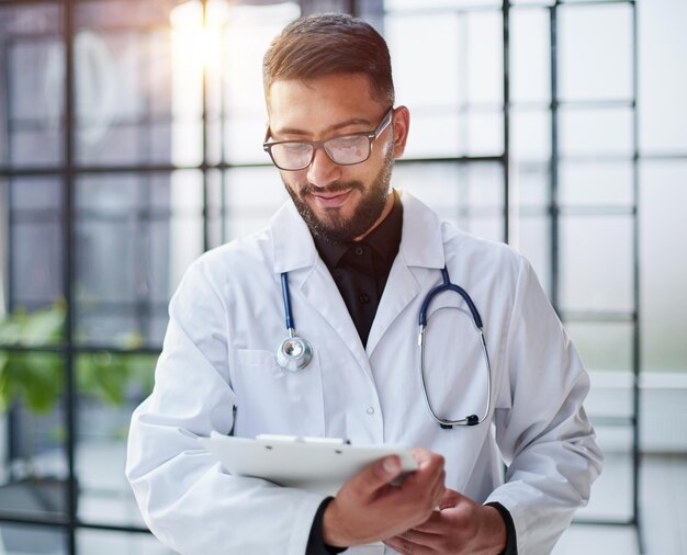 Sorriso médico masculino com os braços cruzados no hospital