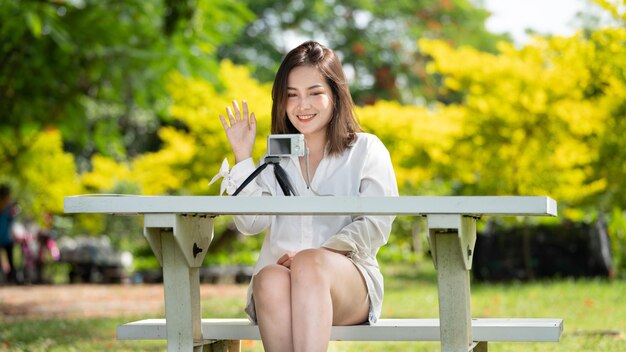 Sorriso pensativo Mulher feliz fazendo videochamadas online ou se encontrando online trabalhando com um laptop em um parque