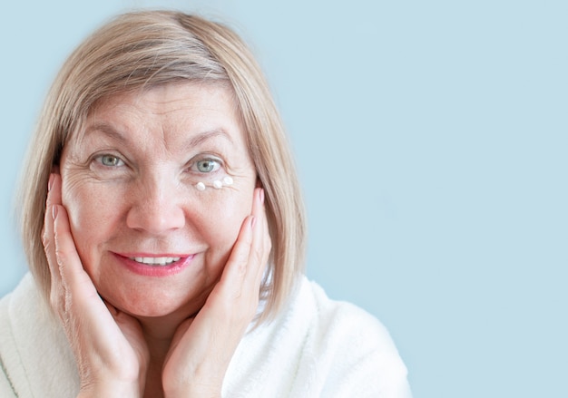 Sorriso sênior de mulher com loção anti-envelhecimento. tratamentos naturais de spa, conceito de cuidado corporal, cosméticos orgânicos. conceito anti-envelhecimento, saúde e cosmetologia, aposentados e pessoas maduras, novos idosos