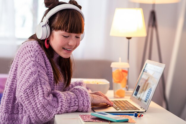 Sorriso sincero. mulher satisfeita ouvindo música enquanto olha para o telefone