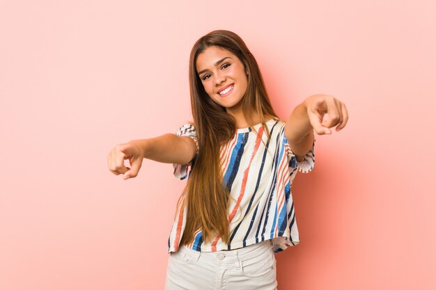 Sorrisos alegres da jovem mulher magro, apontando para a frente.