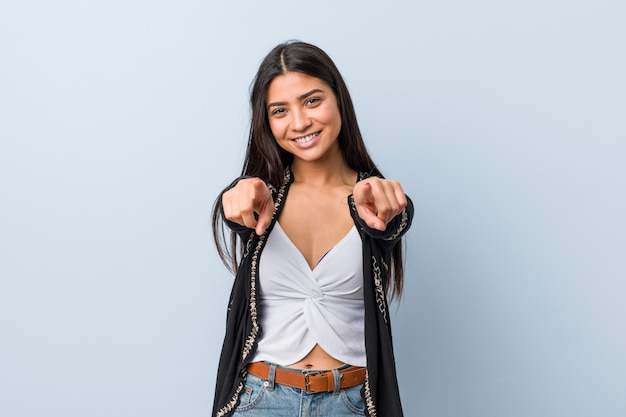 Sorrisos alegres da mulher árabe natural e bonita nova que apontam para a frente.