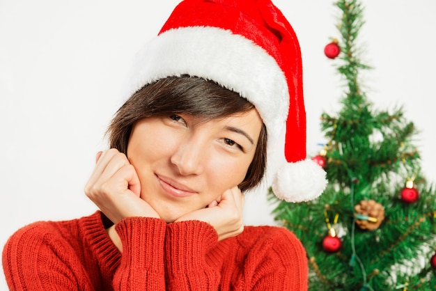 Sorrisos de mulher bonita em um chapéu de Papai Noel