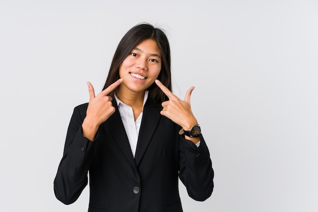 Sorrisos de mulher de negócios asiáticos jovens, apontando os dedos na boca.