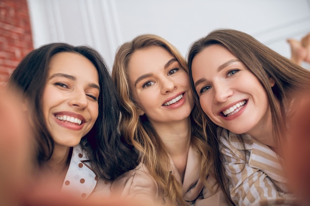 Sorrisos felizes. três garotas fazendo selfie e parecendo felizes