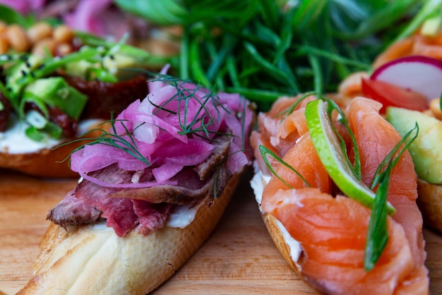 Sortierte Bruschetta mit roten Fischkalkkräutern und Zwiebeln auf einem hölzernen Servierbrett Gesunder und leckerer Snack Nahaufnahme