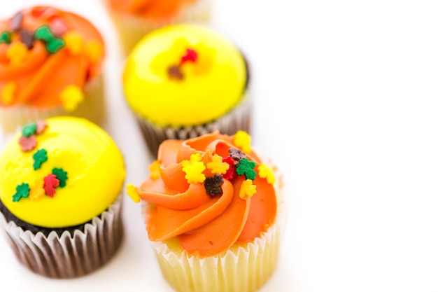 Sortierte Cupcakes mit gelbem und orangefarbenem Zuckerguss, dekoriert für den Herbst.