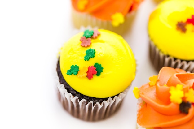 Sortierte Cupcakes mit gelbem und orangefarbenem Zuckerguss, dekoriert für den Herbst.