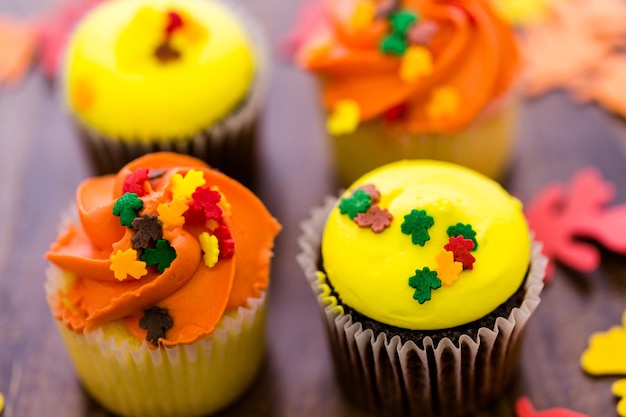 Sortierte Cupcakes mit gelbem und orangefarbenem Zuckerguss, dekoriert für den Herbst.