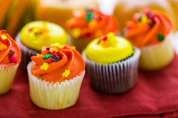 Sortierte Cupcakes mit gelbem und orangefarbenem Zuckerguss, dekoriert für den Herbst.