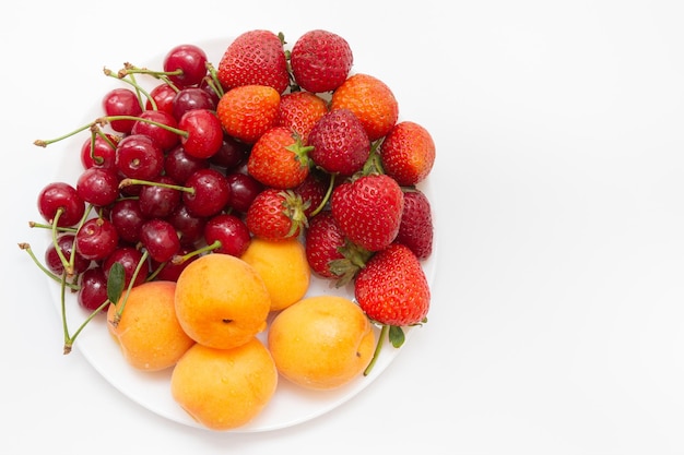 Sortierte Früchte in der weißen Schüssel lokalisiert auf weißem Hintergrund. Schüssel gesundes frisches Obst. Ansicht von oben.