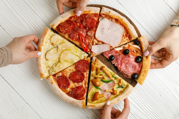 Sortierte italienische Pizza auf einem weißen Holztisch Verschiedene Stücke in einem Portionsset